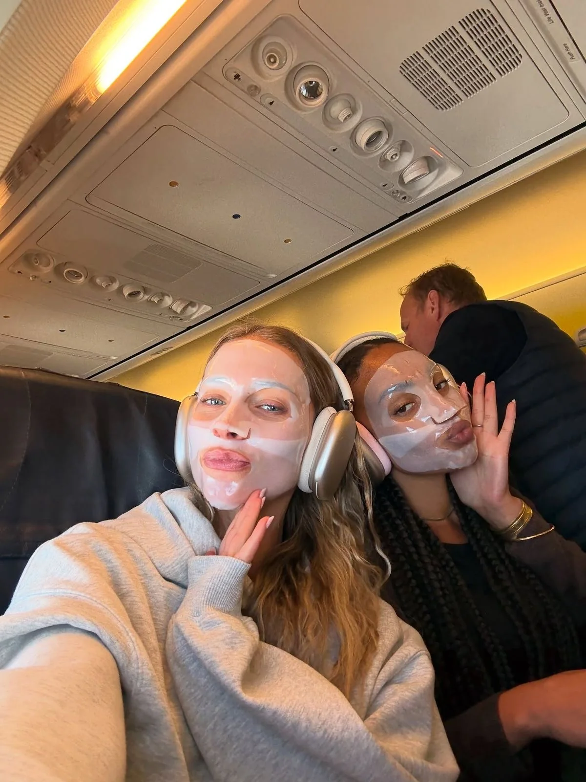 Two travellers wearing sheet masks on board an aircraft